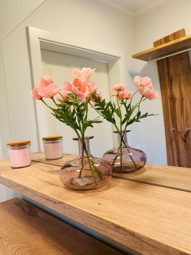 two vases with pink flowers on a wooden shelf at Ferienwohnung in Winterscheid in Ruppichteroth