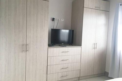 a living room with a tv and wooden cabinets at Conveniente ubicación en zona muy silenciosa Apt 3 in Curridabat