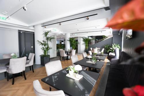 a restaurant with black tables and white chairs at Grand Hotel Coroana in Bistriţa
