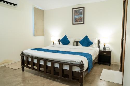a bedroom with a large bed with blue pillows at Dev Bhoomi Farms & Cottages in Dharamshala
