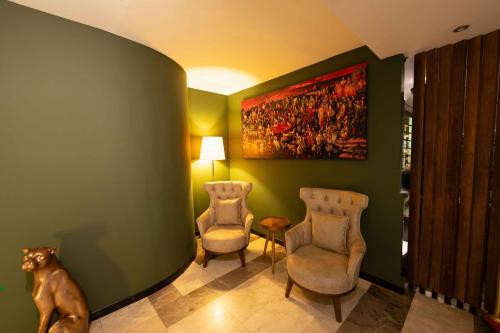 a dog sitting in a room with two chairs and a painting at Boris Hotel Beylikdüzü in Beylikduzu