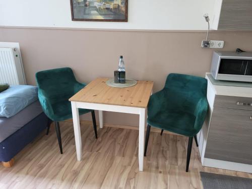 a small room with a table and two green chairs at Zum Fuchsbau - Schöneiche bei Berlin in Schöneiche
