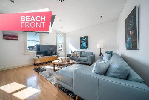 a living room with a blue couch and a tv at Aqua by the Sea - 1BR, Beachfront, Pool & Gym in Henley Beach