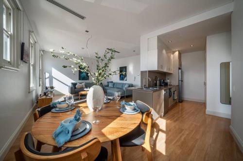 a kitchen and dining room with a wooden table and chairs at Aqua by the Sea - 1BR, Beachfront, Pool & Gym in Henley Beach