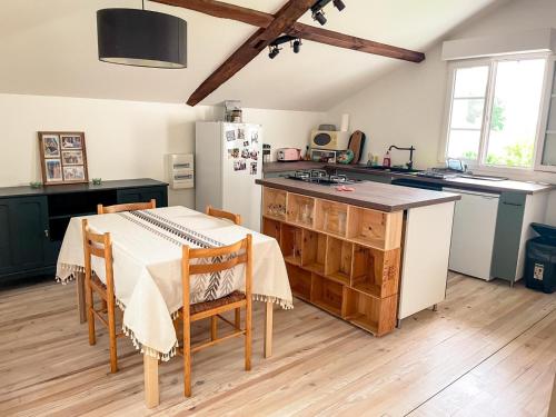 une cuisine avec une table et un réfrigérateur blanc dans l'établissement Gite en appartement en sud ouest, à Saint-Martin-de-Hinx