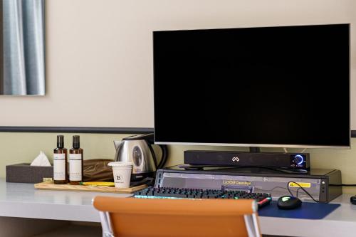 a desk with a computer and a monitor and a keyboard at Brown Dot Hotel Geumchon in Paju
