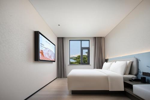a bedroom with a white bed and a tv at Atour Light Hotel Jinan The Laming Lake Scenic Area in Jinan