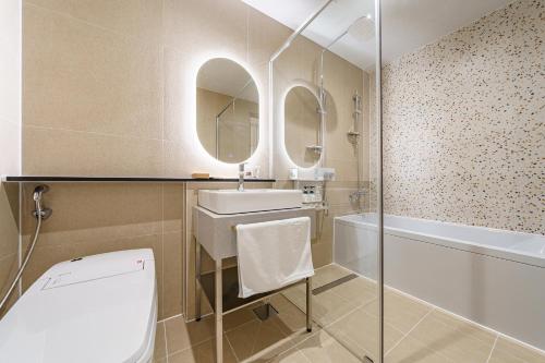 a bathroom with a sink and a tub and a toilet at Brown Dot Hotel Geumchon in Paju