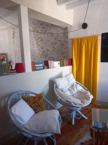 a living room with two chairs and a yellow curtain at La maison aux livres in Rioux-Martin