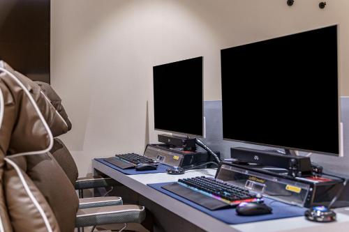 a desk with two computer monitors and a keyboard and mouse at Brown Dot Hotel Geumchon in Paju