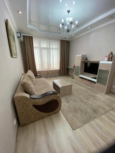 a living room with a couch and a television at Двухкомнатные бизнес апартаменты в ЖК Заман in Atyraū