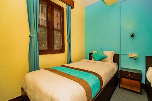 a bedroom with a bed with blue walls and a window at Rest Up Thamel Hostel in Kathmandu