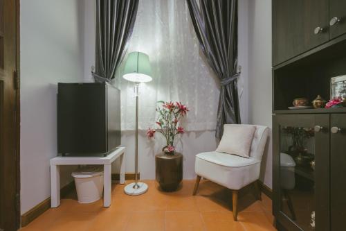 a living room with a tv and a chair and a lamp at Botan Boutique Hotel in Patong Beach