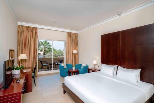 a hotel room with a bed and a balcony at Metropolitan Al Mafraq Hotel in Abu Dhabi