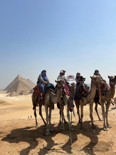 a group of people riding on camels in front of the pyramids at Happy Day Pyramids View Hotel in Cairo