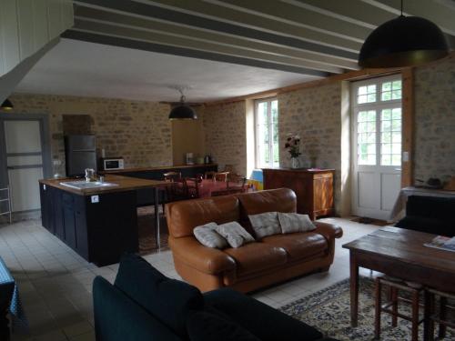 un salon avec un canapé en cuir et une cuisine dans l'établissement LE PIGEONNIER UTAH BEACH, à Sainte-Marie-du-Mont