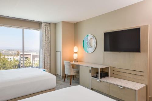 a hotel room with a bed and a desk with a television at Renaissance ClubSport Aliso Viejo Laguna Beach Hotel in Aliso Viejo