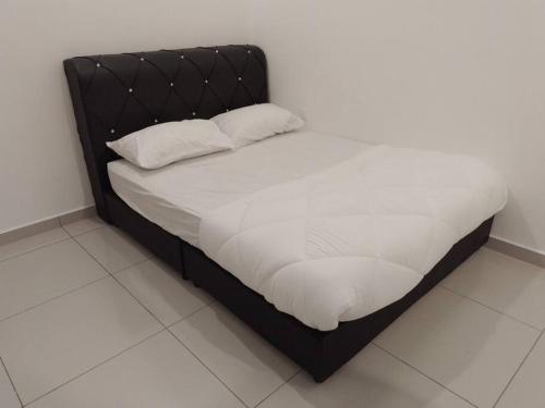 a bed with a black frame and white sheets and pillows at UMMA Homestay Jitra in Jitra