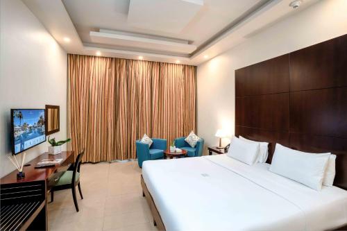 a hotel room with a large bed and a desk at Metropolitan Al Mafraq Hotel in Abu Dhabi