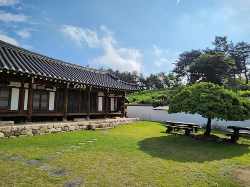 Un edificio con un banco y un árbol en el césped. en Dobong Seodang, en Gyeongju
