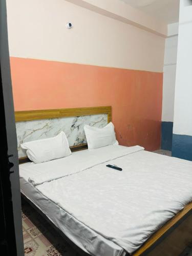 a bed with a cell phone sitting on top of it at Maharishi inn Ayodhya in Faizābād