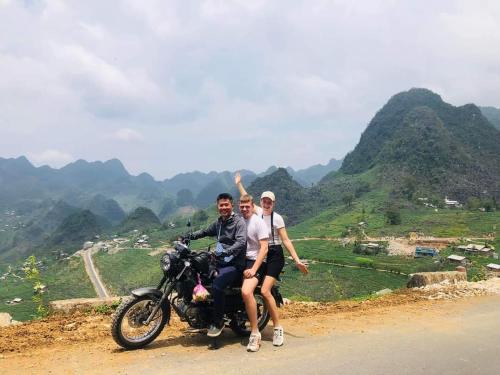 three people sitting on a motorcycle on a road at Homestay field - bungalow, Ha giang loop tour, motorbikes rental in Ha Giang