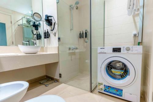 a bathroom with a washing machine and a shower at Metropolitan Al Mafraq Hotel in Abu Dhabi