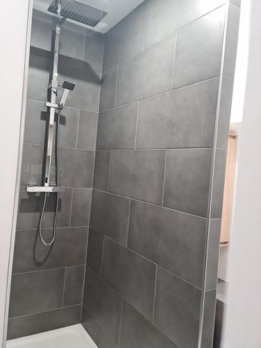 La salle de bains est pourvue d'une douche et d'un mur en carrelage. dans l'établissement Appartement Les Picholines - La tranquillité au cœur d'Anduze, à Anduze