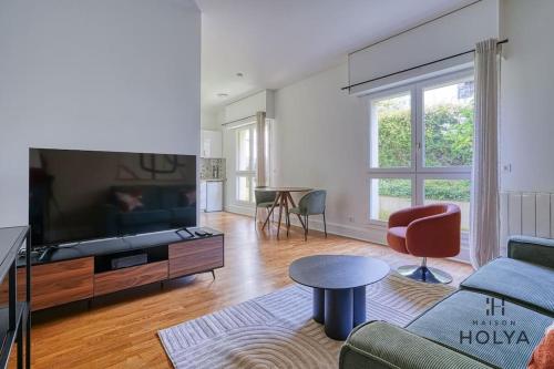 un salon avec un canapé et une télévision dans l'établissement Le Flamboyant - En bordure de Paris - 340B, à Versailles