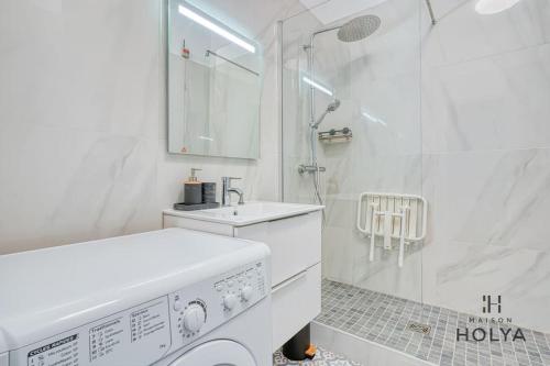 La salle de bains blanche est pourvue d'un lave-linge et d'une douche. dans l'établissement Le Flamboyant - En bordure de Paris - 340B, à Versailles