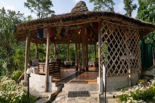 a bamboo pavilion with a table and chairs at Dev Bhoomi Farms & Cottages in Dharamshala