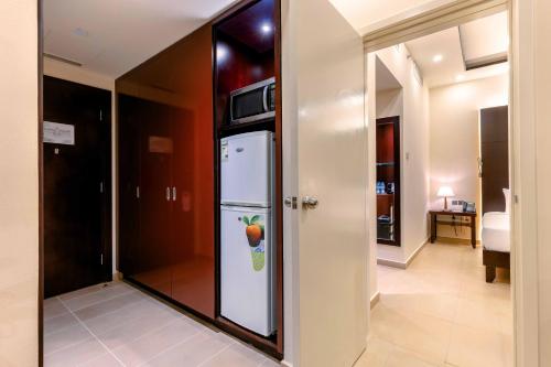a kitchen with a refrigerator with an apple on it at Metropolitan Al Mafraq Hotel in Abu Dhabi