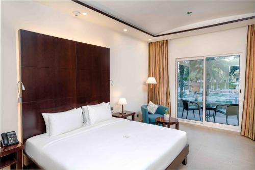 a hotel room with a bed and a view of a table at Metropolitan Al Mafraq Hotel in Abu Dhabi