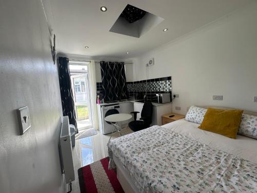 a small bedroom with a bed and a kitchen at Luxury Ensuite Studio In Crayford Dartford Bexley London With Full Kitchen And Side Garden Alleyway Entrance in Slades Green