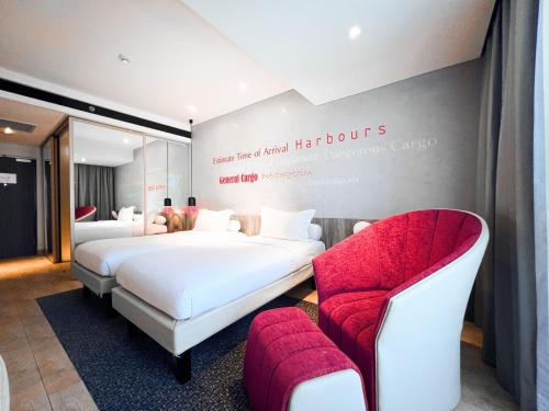 a hotel room with two beds and a chair at ibis Styles Batam Nagoya in Nagoya