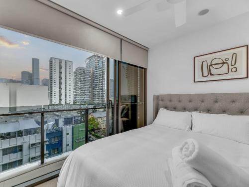 a bedroom with a white bed and a large window at Resort Living 2BR with Pool Spa Gym & Parking in Brisbane