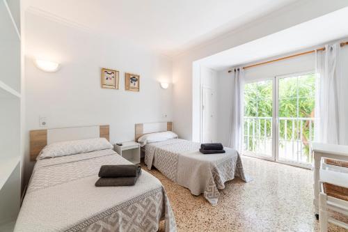 Dos camas en una habitación blanca con ventana. en Hostal Moya, en Roquetas de Mar