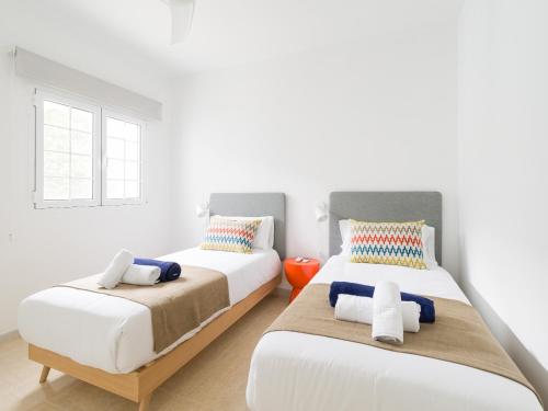 2 Betten in einem Zimmer mit weißen Wänden und einem Fenster in der Unterkunft Magnífico Timón 8 in Pasito Blanco