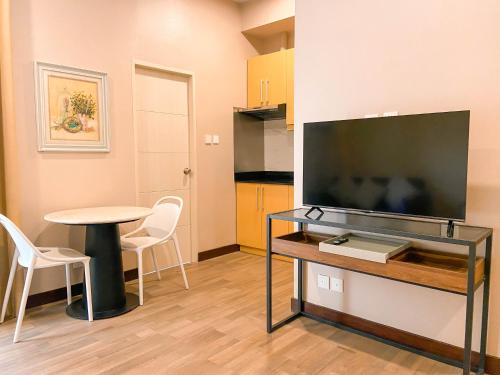 a living room with a tv and a table with chairs at Staycity Serviced Apartment in Cebu City