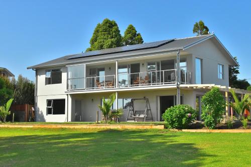 a large white house with a lawn in front of it at Athenree Beach House in Athenree