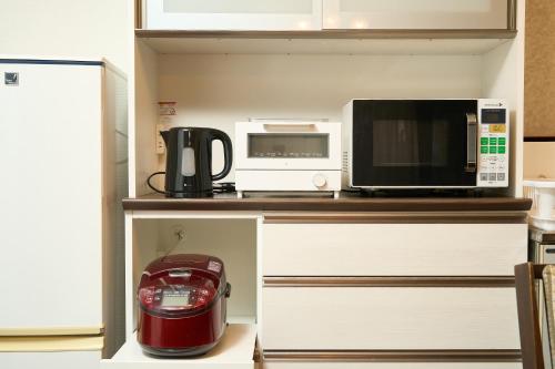 a kitchen with a coffee maker and a microwave at 堀田フォレストハウス in Beppu