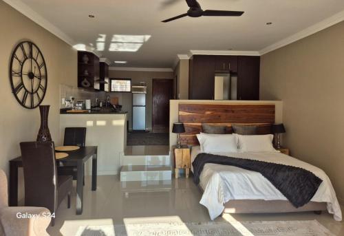 a bedroom with a bed and a table and a kitchen at Hornbill Self Catering Cottages Muldersdrift in Krugersdorp
