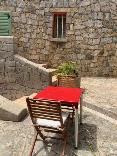 une table et une chaise avec une table rouge dans l'établissement Studio avec piscine Ruppione, à Pietrosella