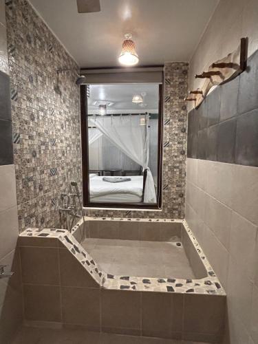 a bathroom with a bath tub with a mirror at Shivam bnb Boutique Apartments in Mandrem