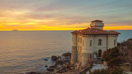a lighthouse on a cliff near the ocean at sunset at Suite al Castello Boccale Terrazza sul Mare in Livorno