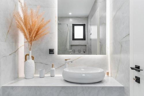 a white bathroom with a sink and a mirror at Infinity Luxury Villas, Lefkada in Athanion