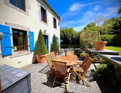 a patio with a wooden table and chairs at Granary at Kergudon Gîtes, family gîte with pool in Sizun
