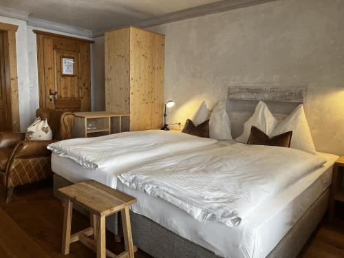 a bedroom with a large white bed and a chair at Hotel Berghof in Zermatt
