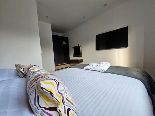 a bedroom with a large white bed with a tv on the wall at Apollo 16-1 bed town center in Luton