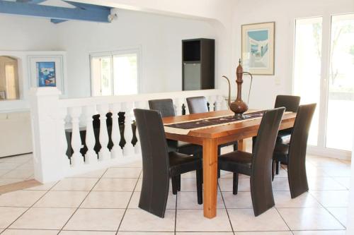 une salle à manger avec une table en bois et des chaises noires dans l'établissement Villa Colombe, vaste jardin, 30 min des plages, à Callian